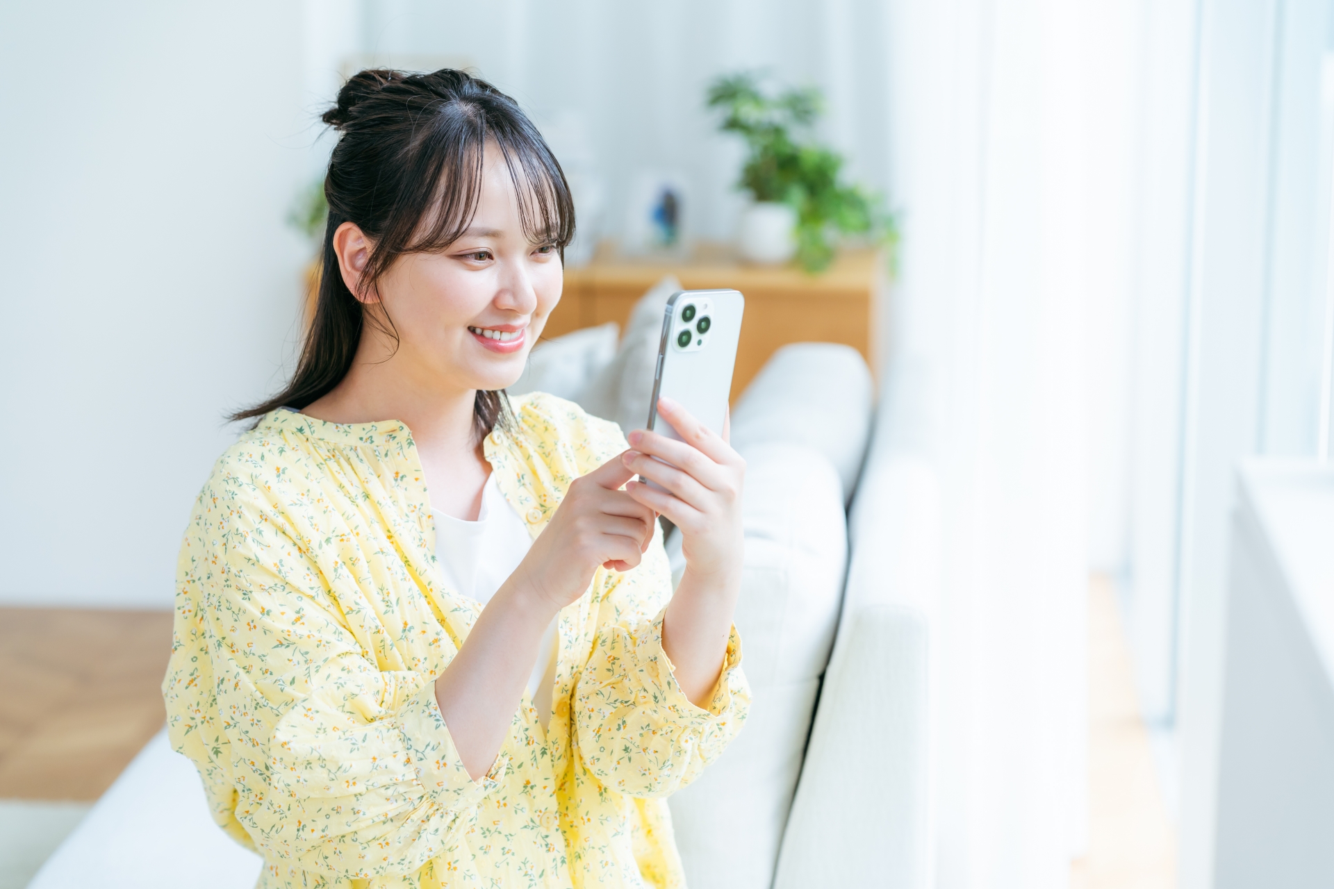 自宅でスマートフォンを使う女性のイメージ